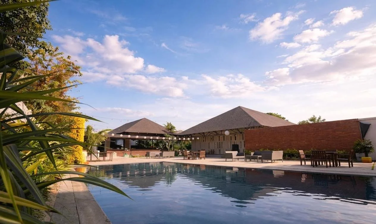 The swimming pool reflecting the sky beside tropical planting and the poolside pavilions