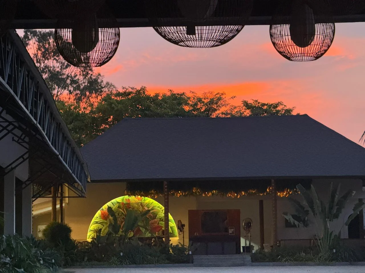 Pink and orange sunset above the courtyard and illuminated restaurant mural