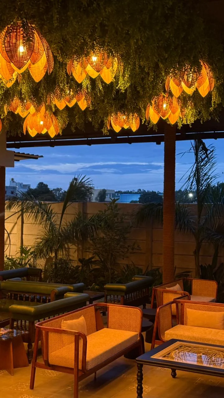 Woven lamps glowing above lounge seating in the evening