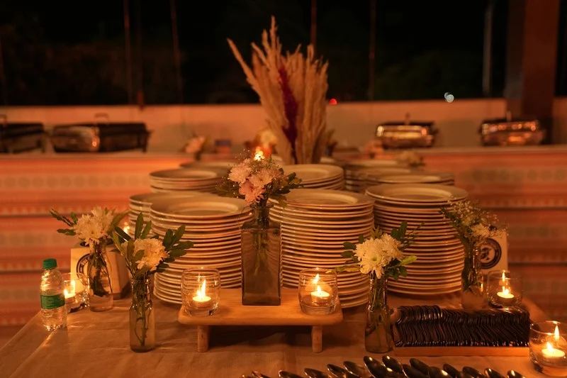 A candlelit table set with stacked plates and dried flowers