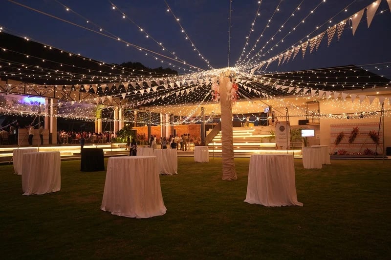 Cocktail tables and bunting on Padma Lawns at dusk