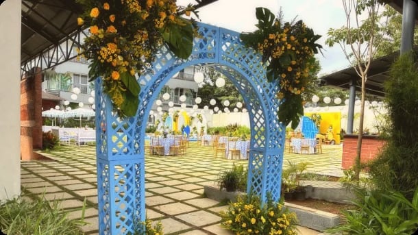 A blue floral arch on the lawn with cocktail tables