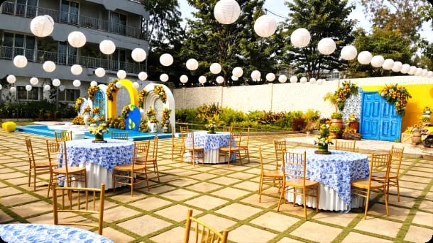 Blue-draped tables under paper lanterns beside the pool
