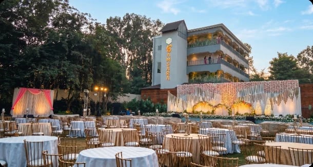 Round tables set on the lawn in front of a reception stage